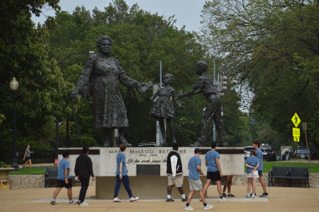 Students standing in front of statue of a woman and two children