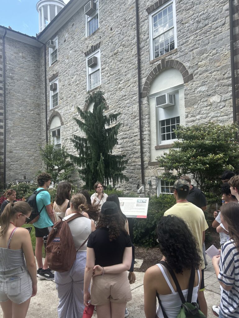 Girl speaks to audience in front of stone building