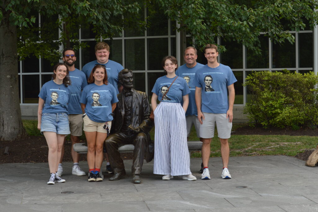 Seven people standing around a statue of Abe Lincoln