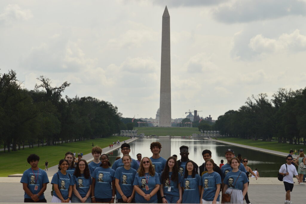 Large group standing in front of Washington Monument and reflecting pool