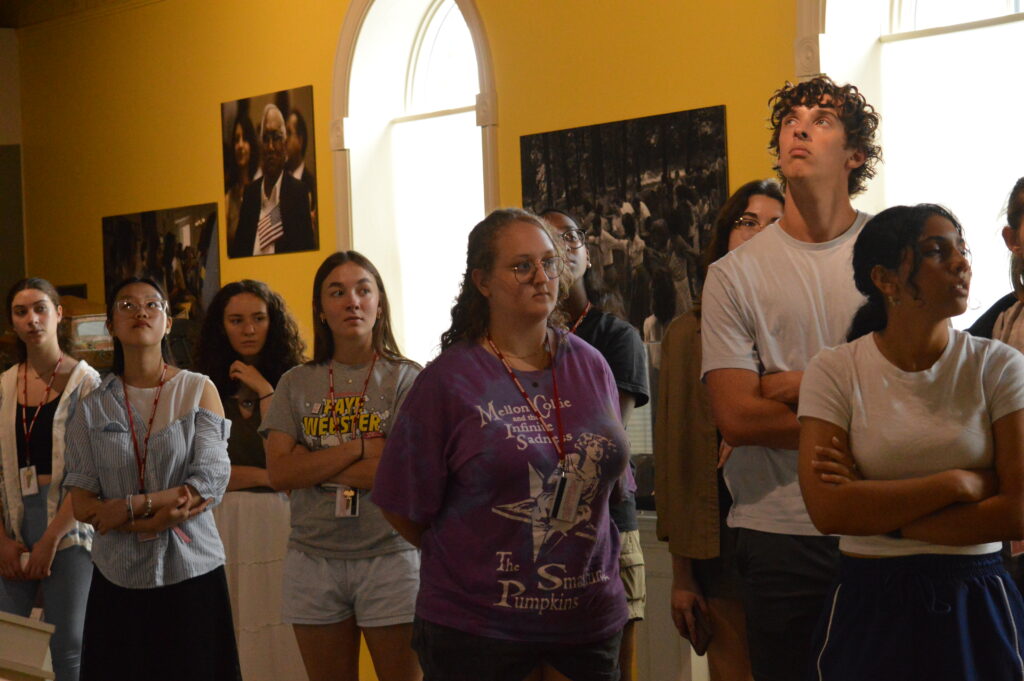 Students standing in front of wall with photos
