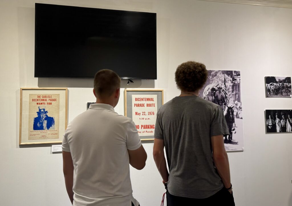 Two boys standing in front of a museum exhibit of posters
