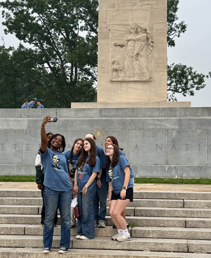 A group of girls taking a selfie on the stairs in front of a white marble monument