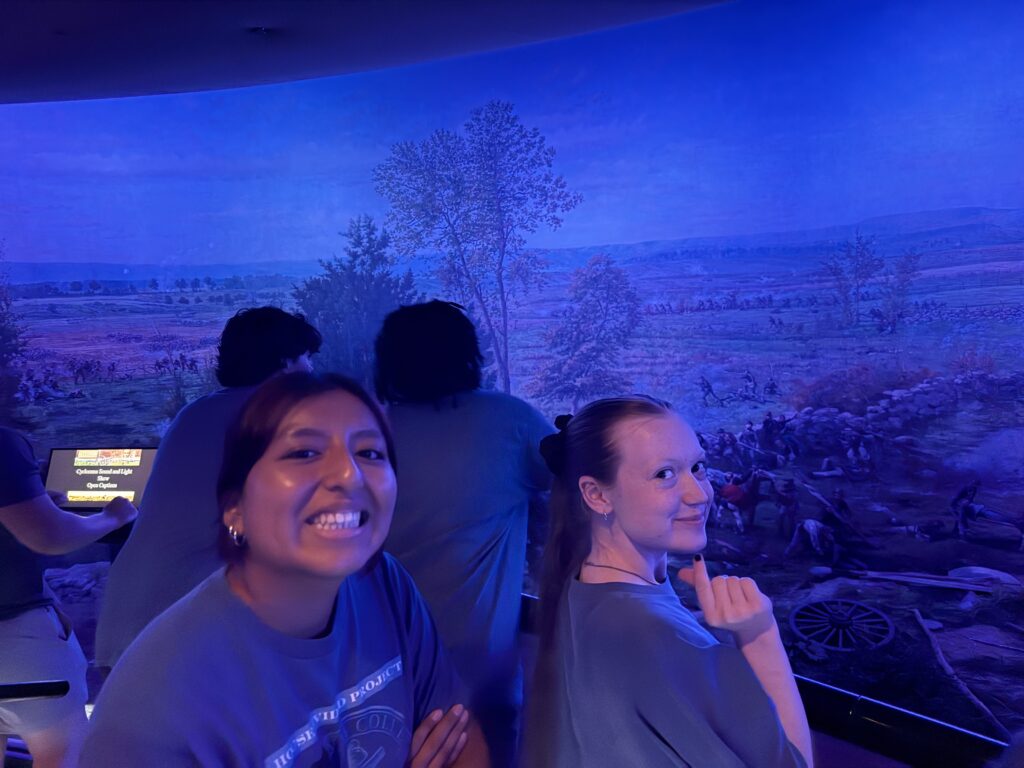 Two girls smiling in front of a painting