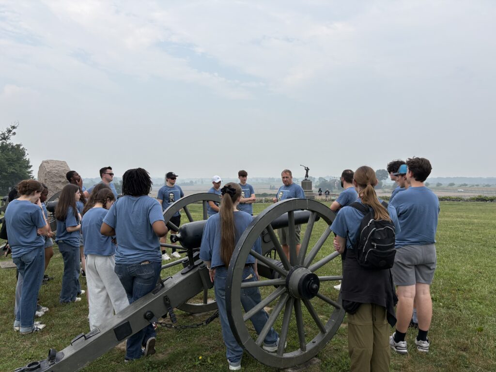 Students standing around another cannon, Professor Pinsker talking