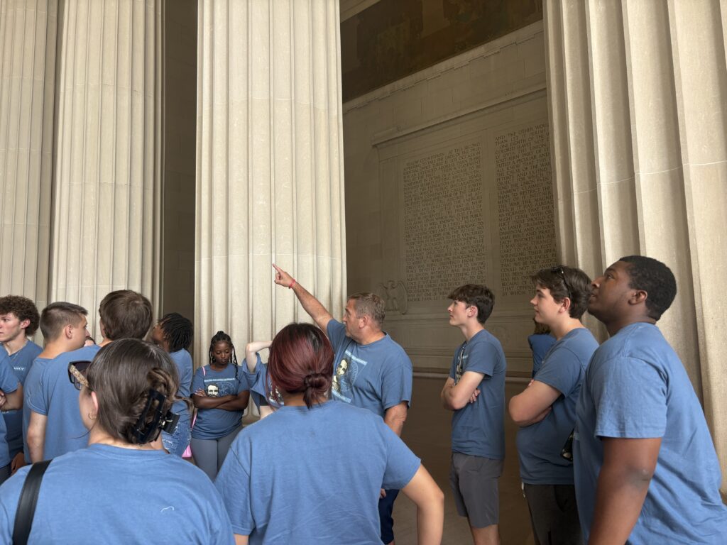 Professor Pinsker pointing to Lincoln at the memorial, kids looking in that direction