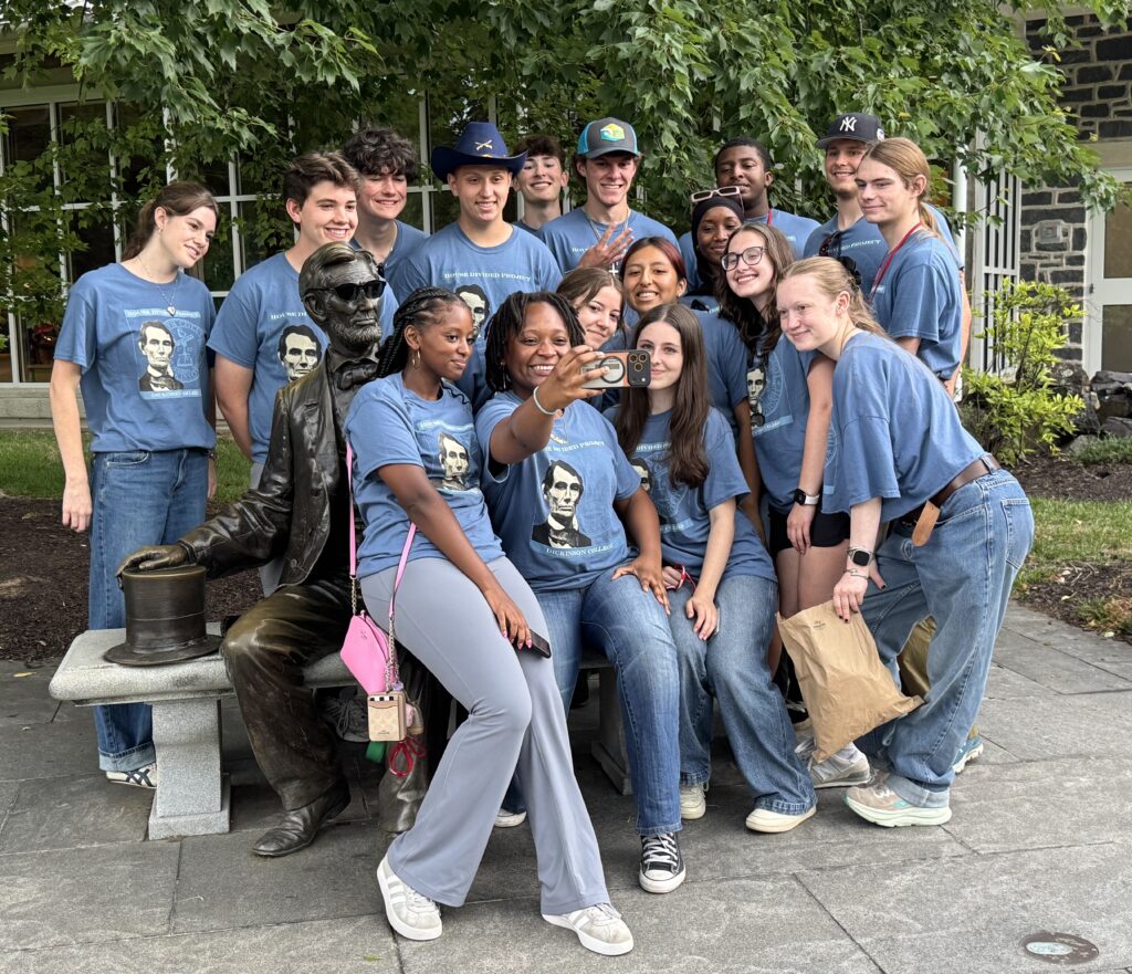 A group of people taking a selfie with a statue of Abe Lincoln