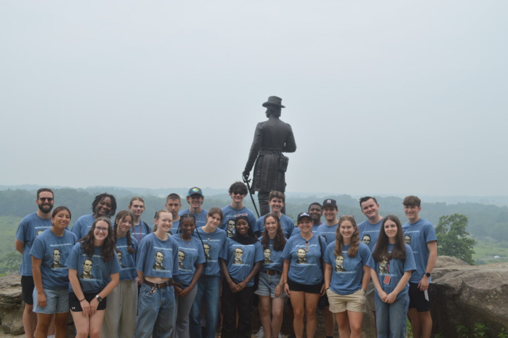 A large group of people standing in front of a statue of a man