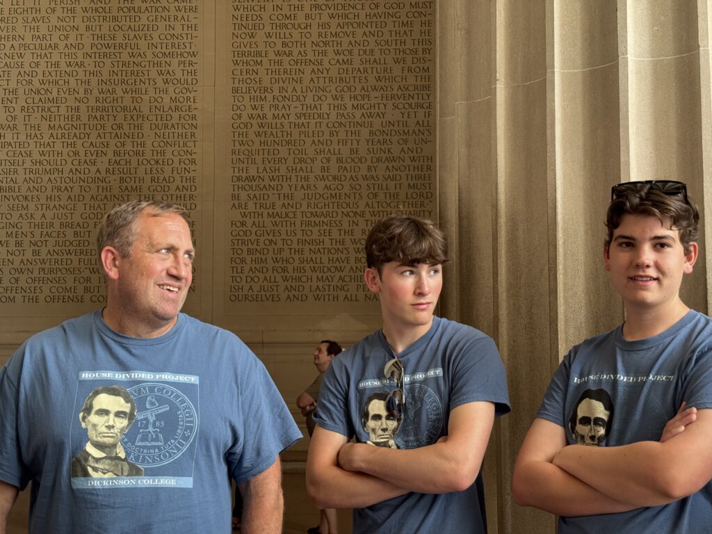 Three people in blue shirts standing in a marble hall