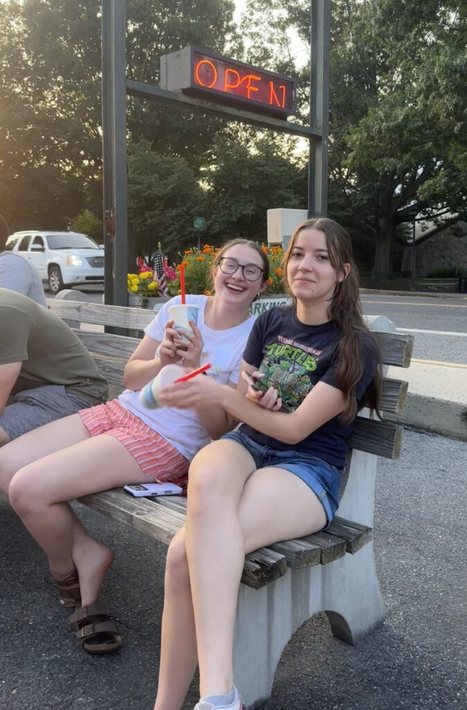 Two girls sitting on a bench and holding ice cream
