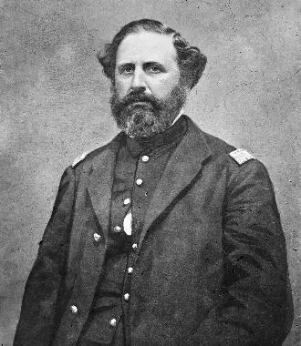 Black and white photograph of US general Speed Smith Fry, wearing an overcoat with epaulettes, and a military uniform with buttons underneath. Fry has dark hair and facial hair. 