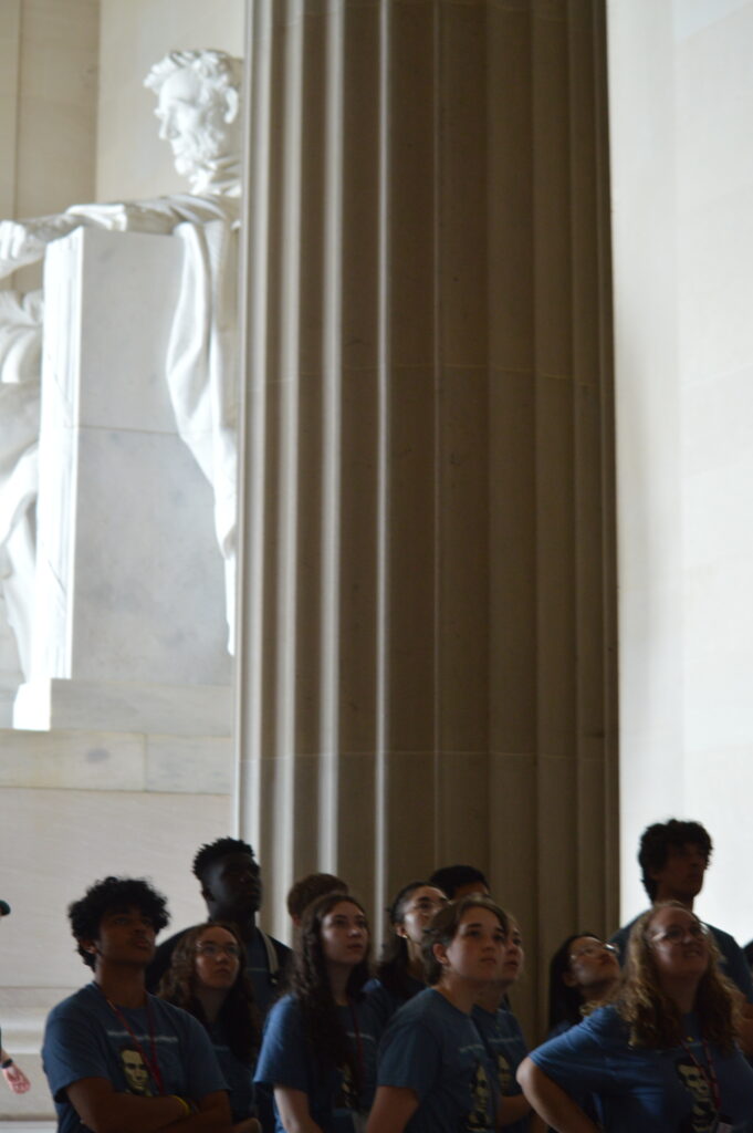 Students looking upward with a statue of Abraham Lincoln in the back