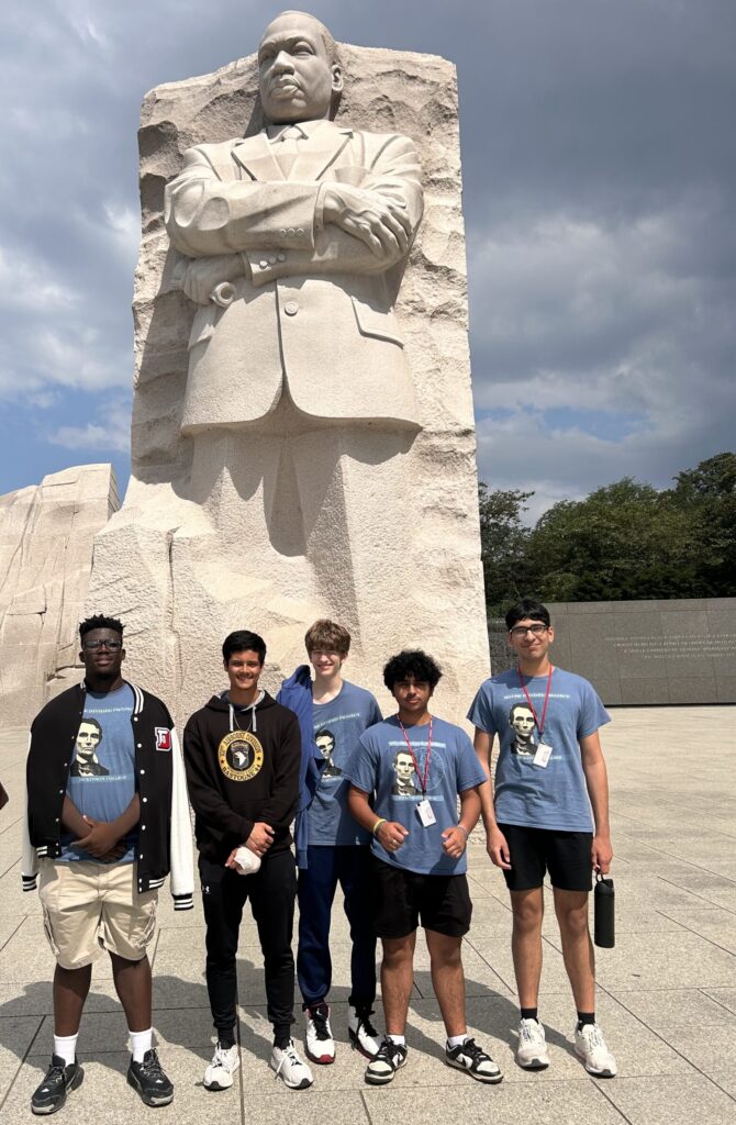 Five students standing in front of a large stone statue of Martin Luther King, Jr.