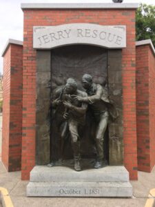 monument, men coming out of bronze plaque, brick structure